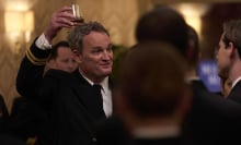 A man raises his glass in a crowded event.