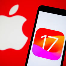 phone displaying ios 17 logo in front of backdrop showing apple logo